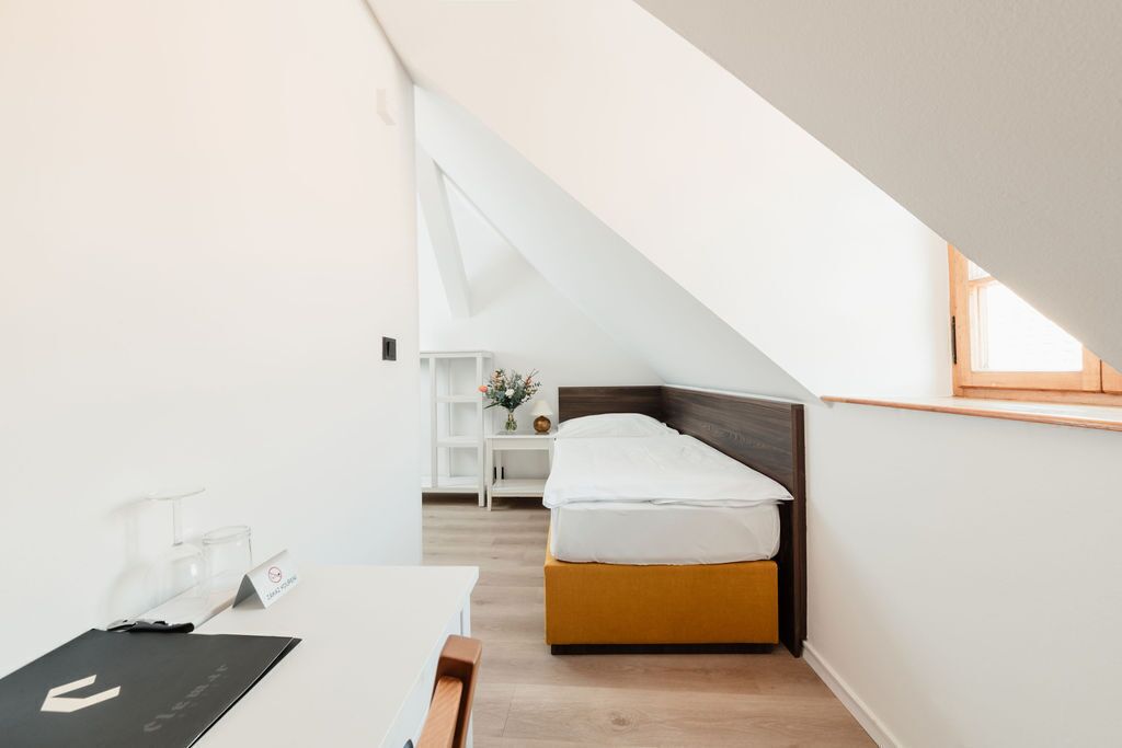 Een moderne, goed verlichte kamer met een bed, een bureau en een klein nachtkastje.