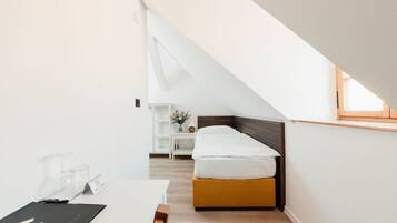 Een moderne, goed verlichte kamer met een bed, een bureau en een klein nachtkastje.