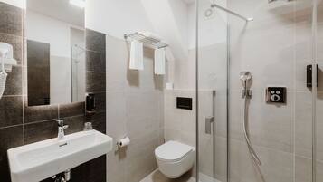 A modern bathroom with a glass-enclosed shower, a white sink, and a toilet.