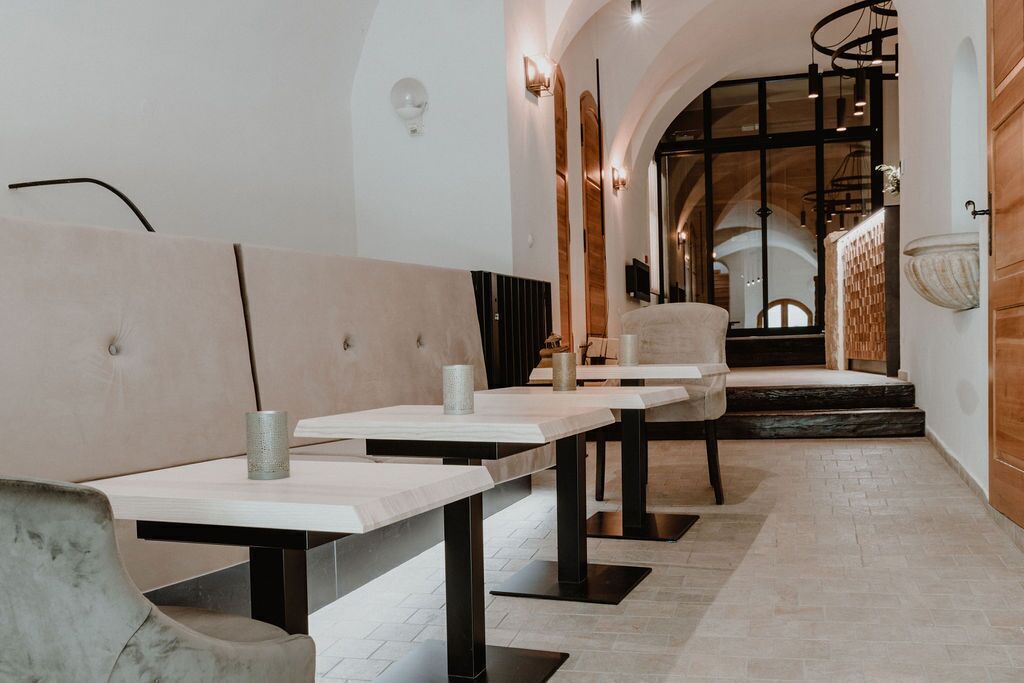 A modern interior with a long dining area featuring tables and chairs, a staircase leading to an upper level, and a minimalist design with neutral colors.
