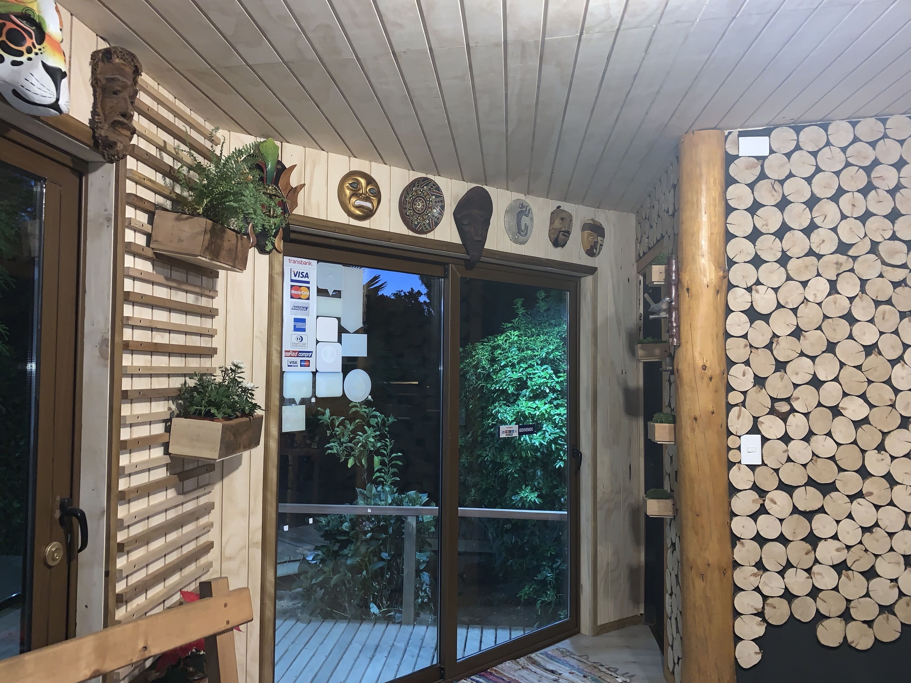 Une façade en bois avec une porte en verre, des lambris en bois et un mur décoré de motifs circulaires en bois.