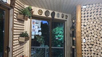 Une façade en bois avec une porte en verre, des lambris en bois et un mur décoré de motifs circulaires en bois.