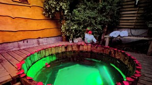 A wooden deck with a circular hot tub surrounded by red flower petals. - Cabañas Pewma Futrono (Futrono)