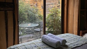 A room with a bed, a window, and a view of an outdoor area with a table and chairs. - Cabañas Pewma Futrono (Futrono)