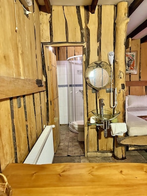 A rustic bathroom with wooden walls, a glass sink, a toilet, and a shower. - Cabañas Pewma Futrono (Futrono)