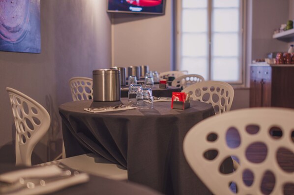 A dining area with a table set for two, featuring a black tablecloth, a stainless steel water bottle, and a red box.