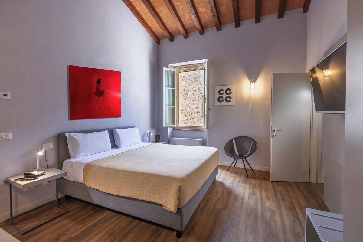 Une chambre à coucher avec un lit, une table de chevet et une fenêtre donnant sur un beau paysage.