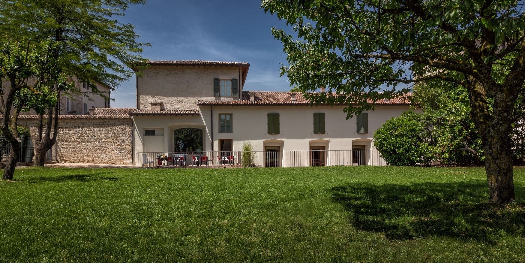 A building with a stone facade, a tiled roof, and a grassy courtyard.