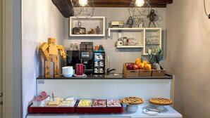 Un buffet de petit-déjeuner proposant une variété d’aliments, une machine à café, ainsi qu’une exposition de radios et de figurines anciennes.