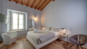 A bedroom with a bed, a chair, a desk, a lamp, and a window.