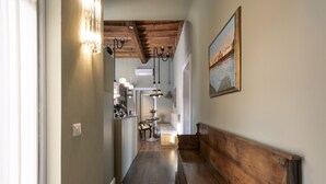 A hallway with a wooden bench, a dining area with a table and chairs, and a painting on the wall. - Parione Uno (Florence)