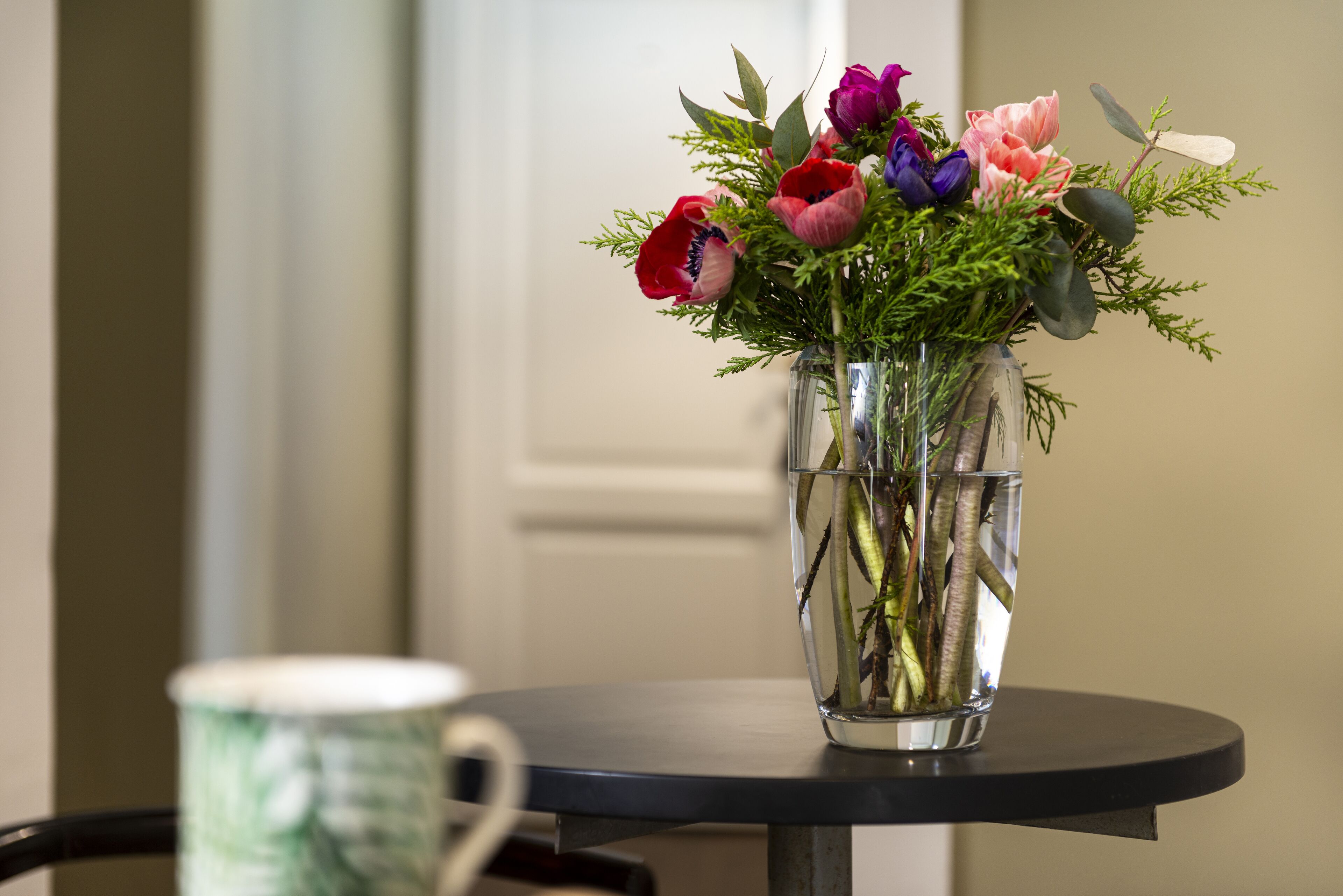 A clear glass vase with a bouquet of flowers on a round table.