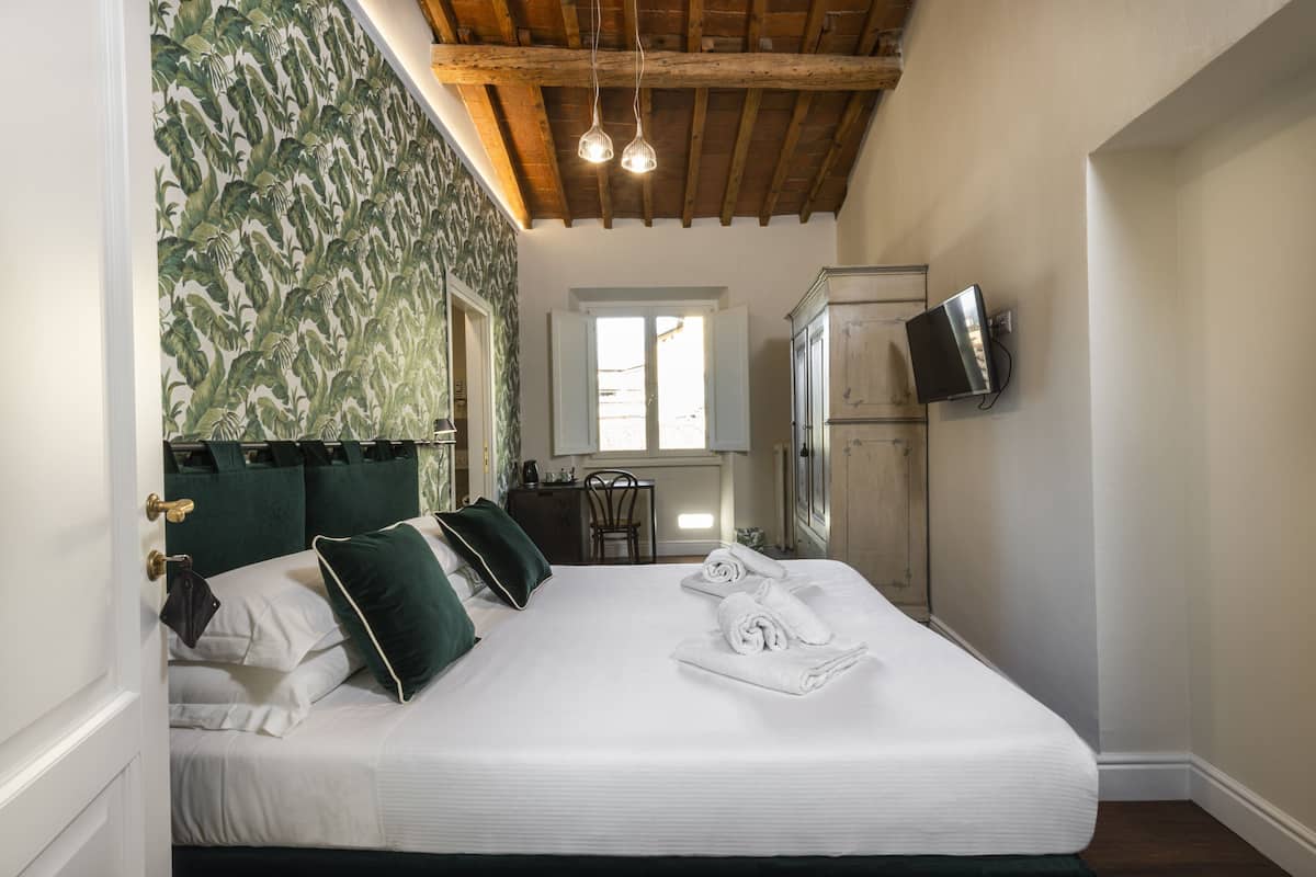 A bedroom with a bed, a television, a wardrobe, and a window.