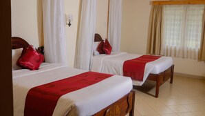 Quarto de hotel com duas camas de solteiro, cada uma com um cobertor e travesseiro vermelhos.