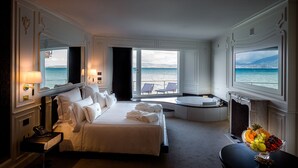 A hotel room with a bed, a sitting area with a view of the sea, and a fruit bowl on a table. - Relais La Speranzina (Sirmione)