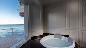 A private bathroom with a bathtub, a window overlooking the sea, and a wooden deck. - Relais La Speranzina (Sirmione)