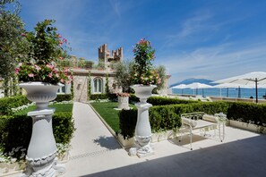 Un patio con urnas blancas, un área de estar al aire libre en blanco y vistas a una estructura similar a un castillo.