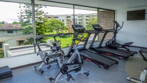 A gym with stationary bikes, treadmills, and a rowing machine. - MG Hotels & Suites (Rionegro)