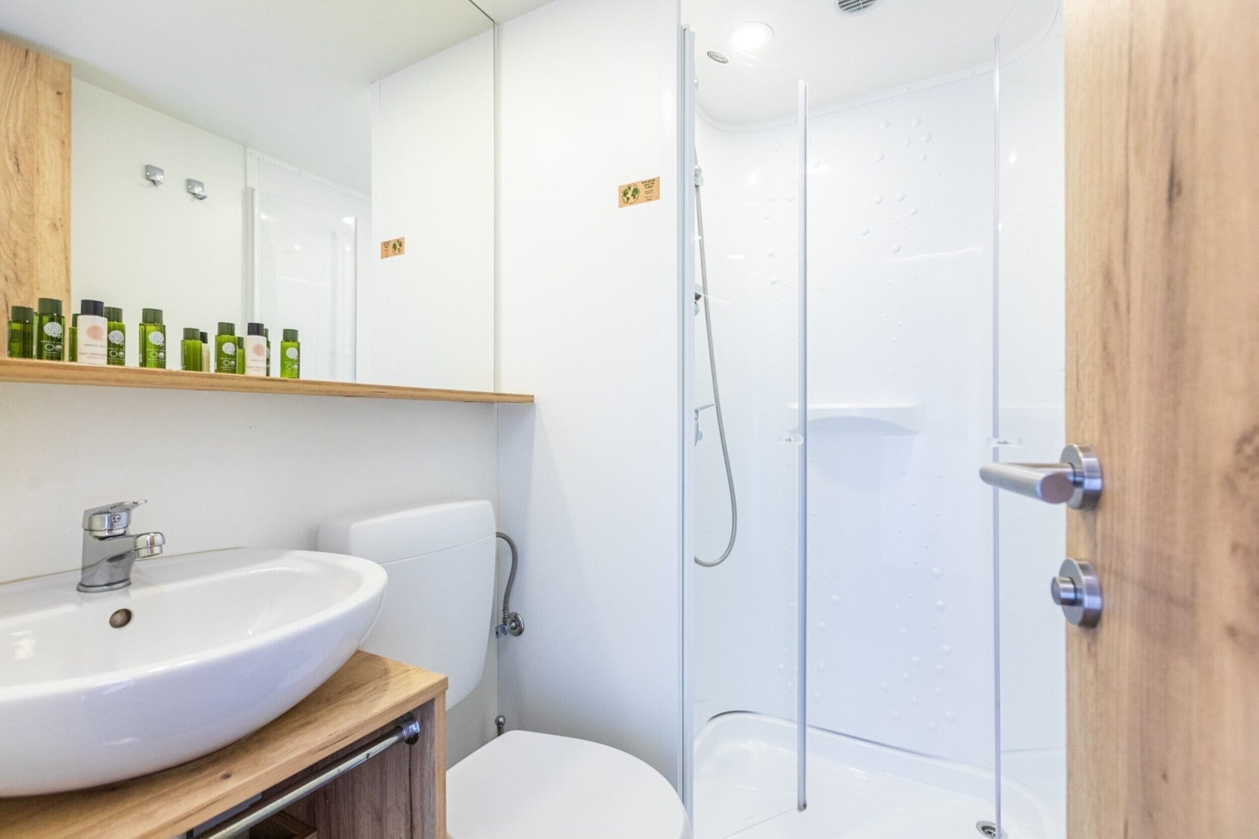 A modern bathroom with a white sink, toilet, and glass shower enclosure.