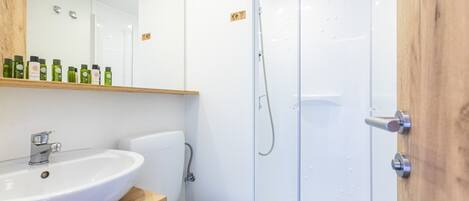 A modern bathroom with a white sink, toilet, and glass shower enclosure.