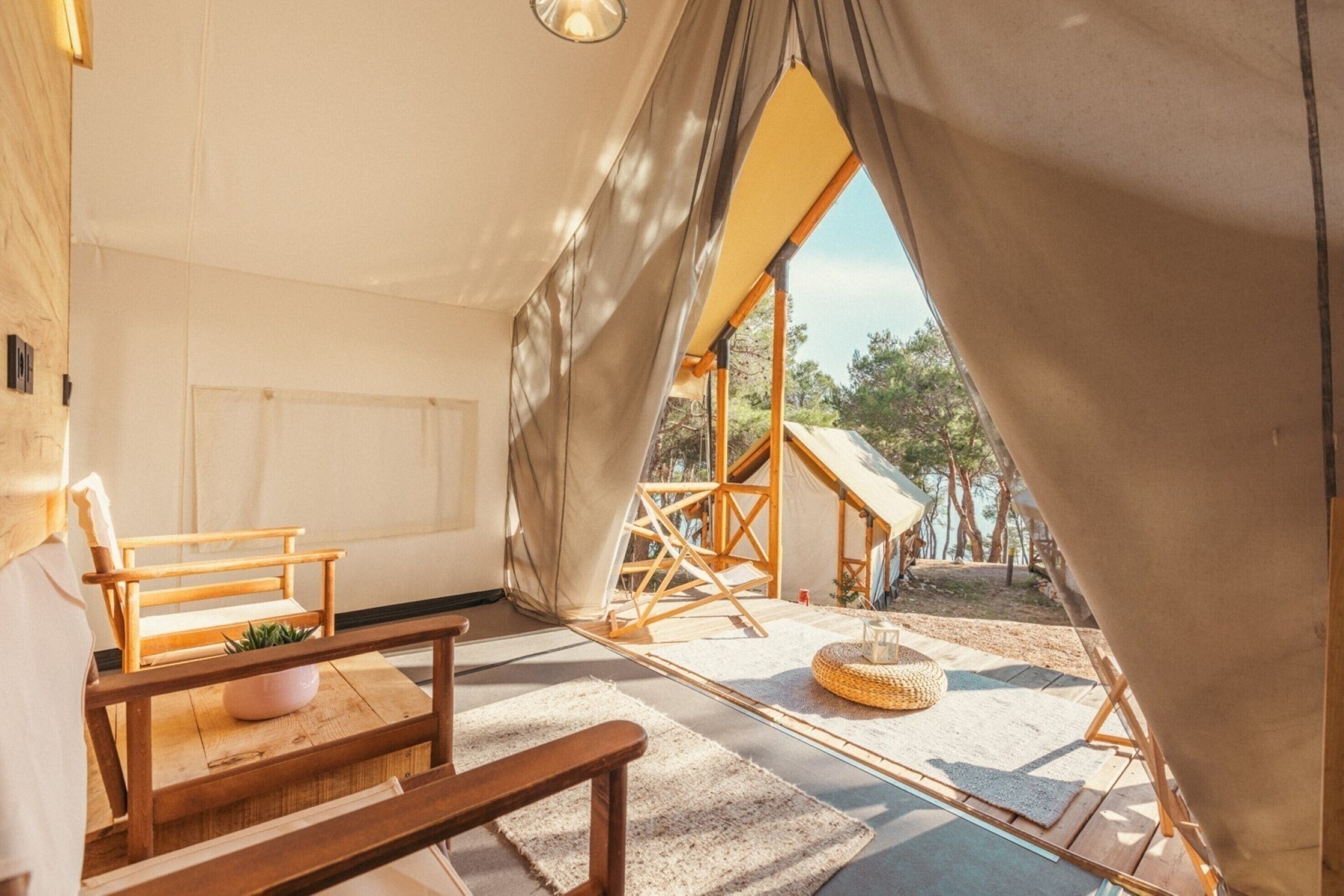 A cozy interior with a wooden bench, a small table, and a view of a tented area outside.