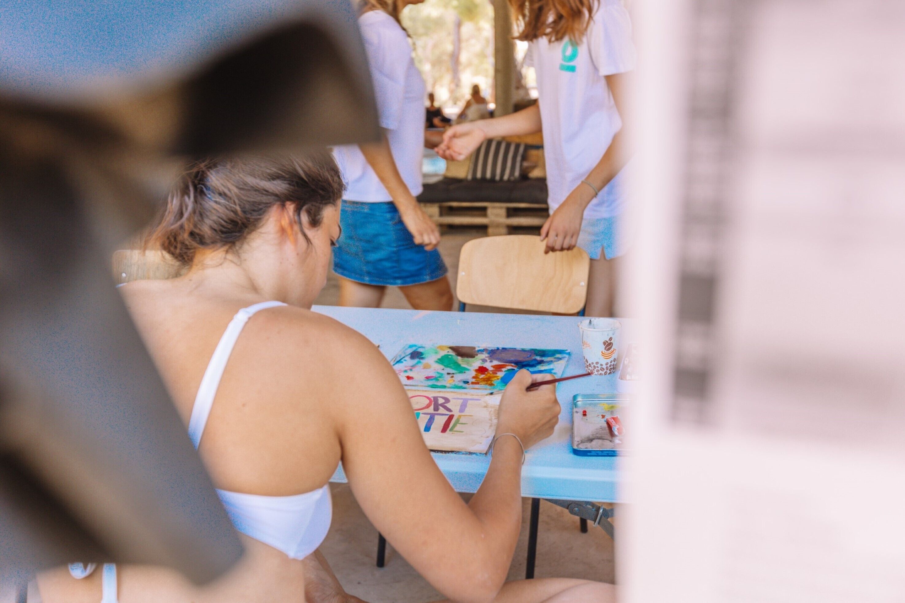 Une personne est en train de peindre sur une toile, assise à une table.