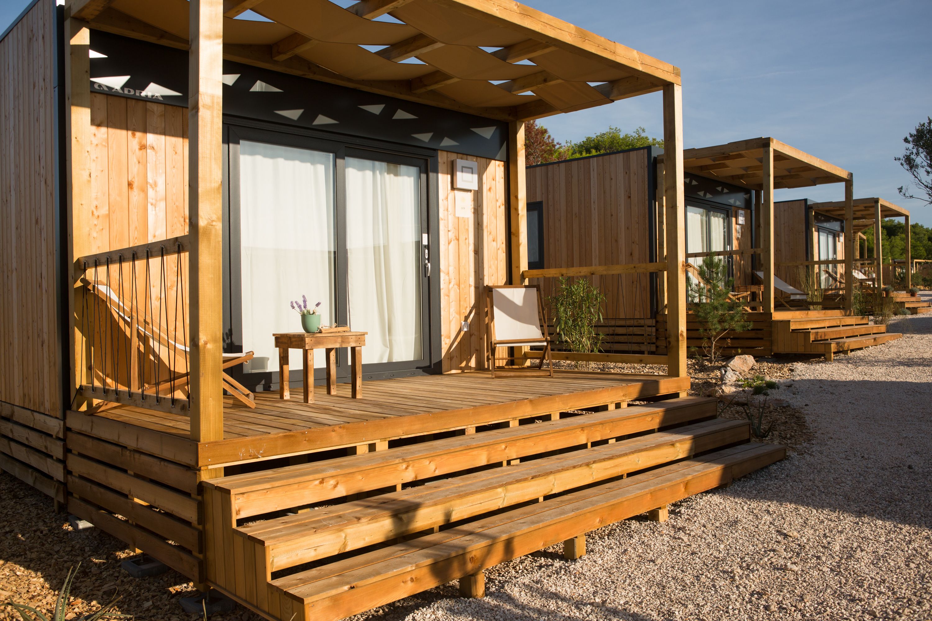 A wooden cabin with a deck, a small table, and a chair.