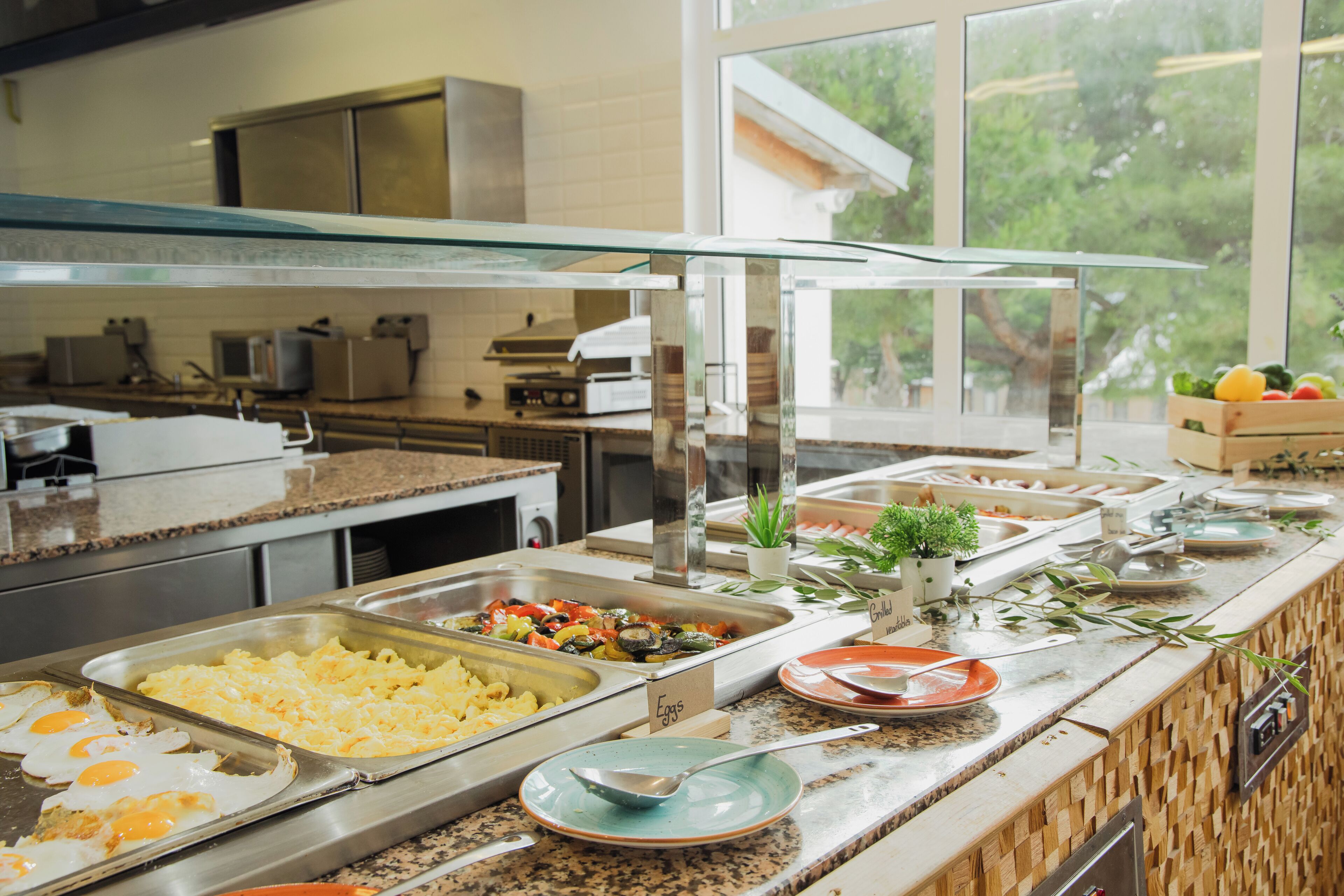 Un montaje tipo bufé con varias estaciones de comida, que incluyen huevos, verduras y frutas.