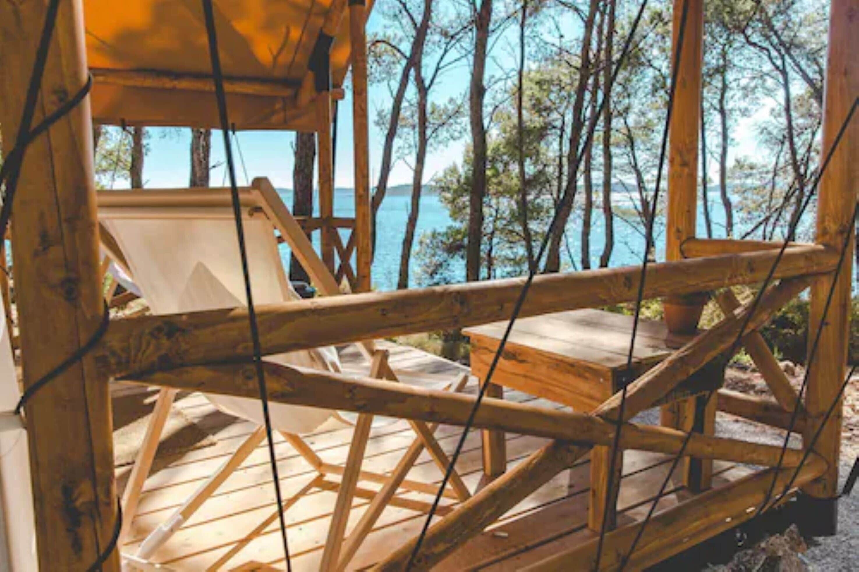 A wooden deck with a railing overlooking a body of water and trees.