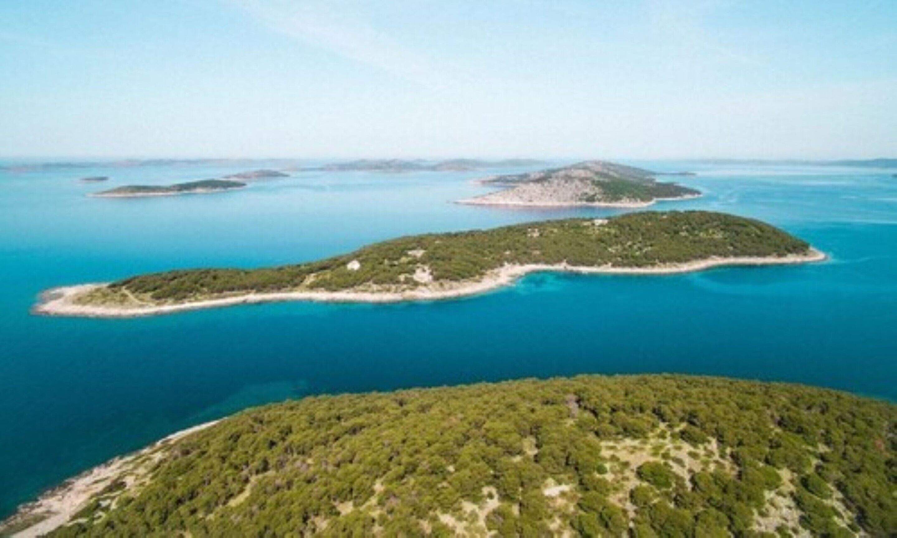 An aerial view of a coastal area with several small islands surrounded by clear blue waters.