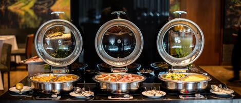 A buffet with various food items and a modern interior with abstract wall art.