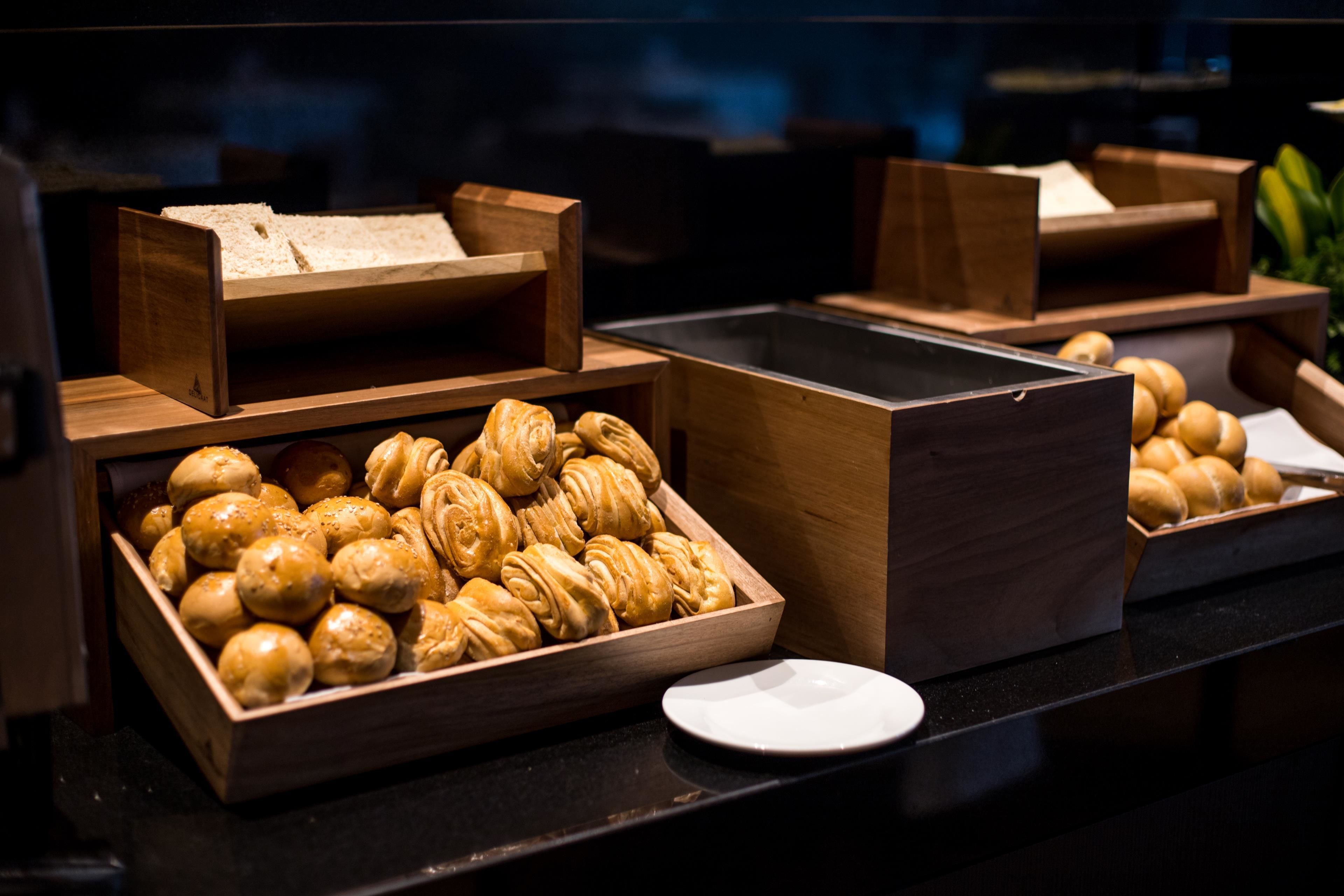 A buffet with various baked goods in wooden trays.
