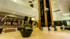 Un vestíbulo amplio con mostrador de recepción, zonas de estar y una gran planta decorativa.