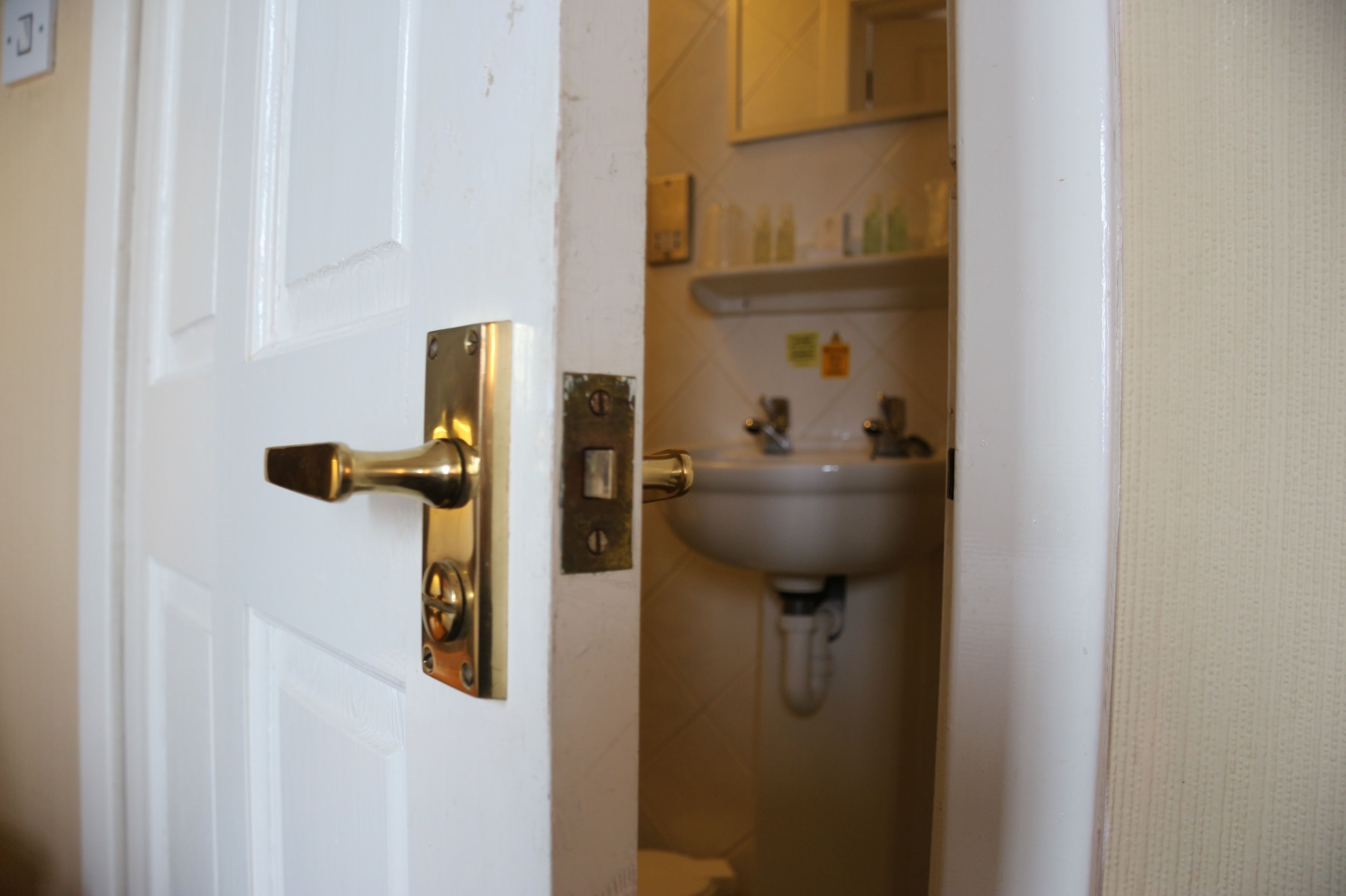 A bathroom with a white door, a sink, and a mirror above it.