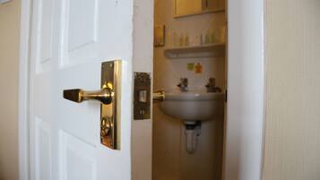 Une salle de bain avec une porte blanche, un lavabo et un miroir au-dessus.