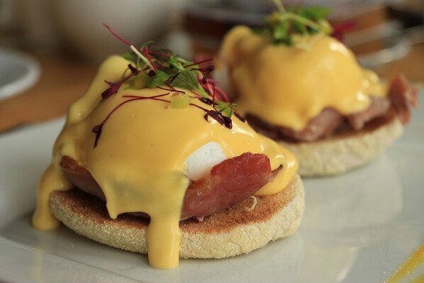 Un plat de petit-déjeuner composé d’œufs, de bacon et de sauce hollandaise, servi sur une tranche de pain.