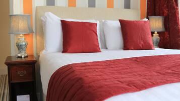 A hotel room with a large bed, red and white bedding, and two bedside lamps.