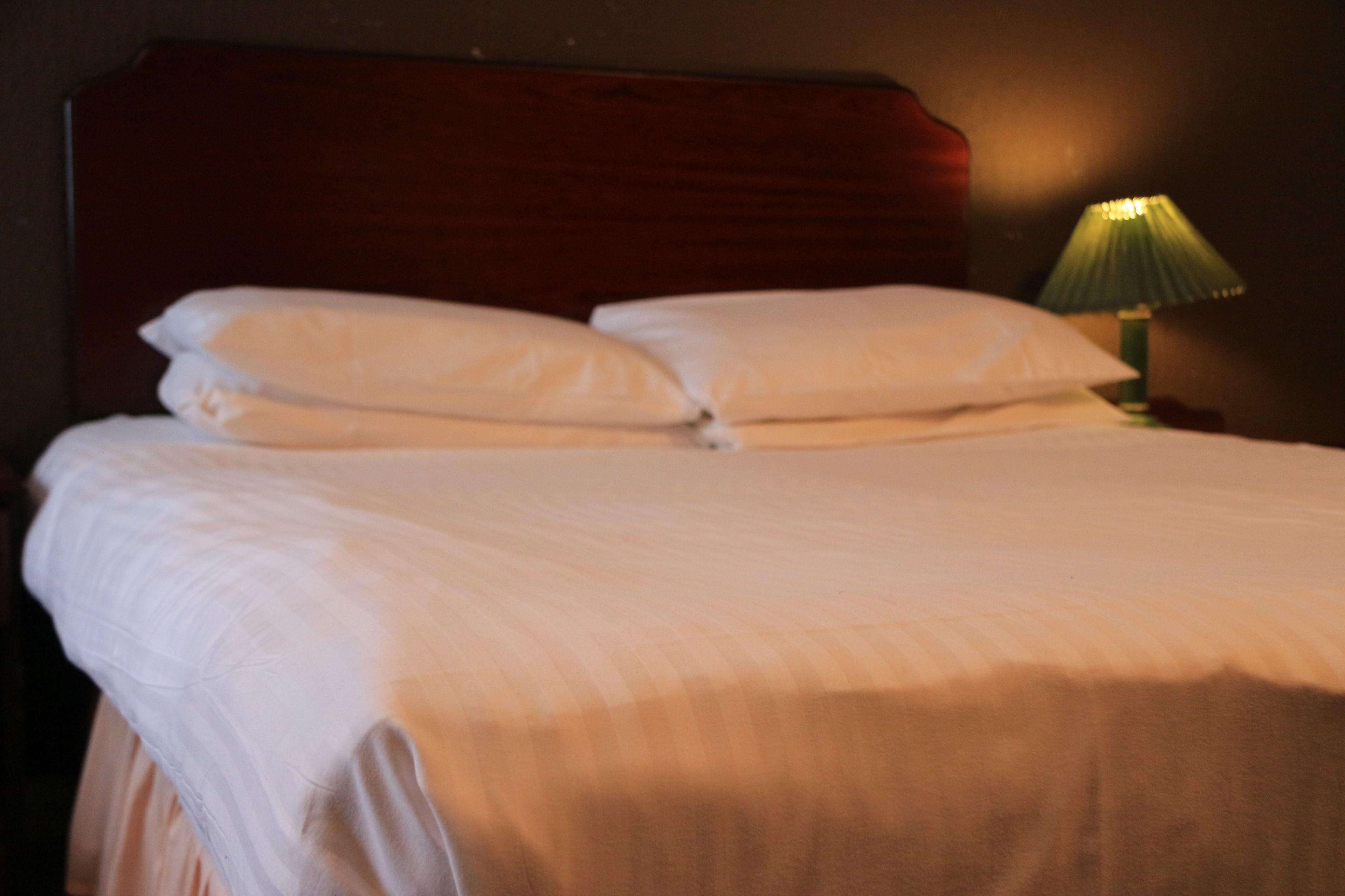 A bed with white linens and a wooden headboard.