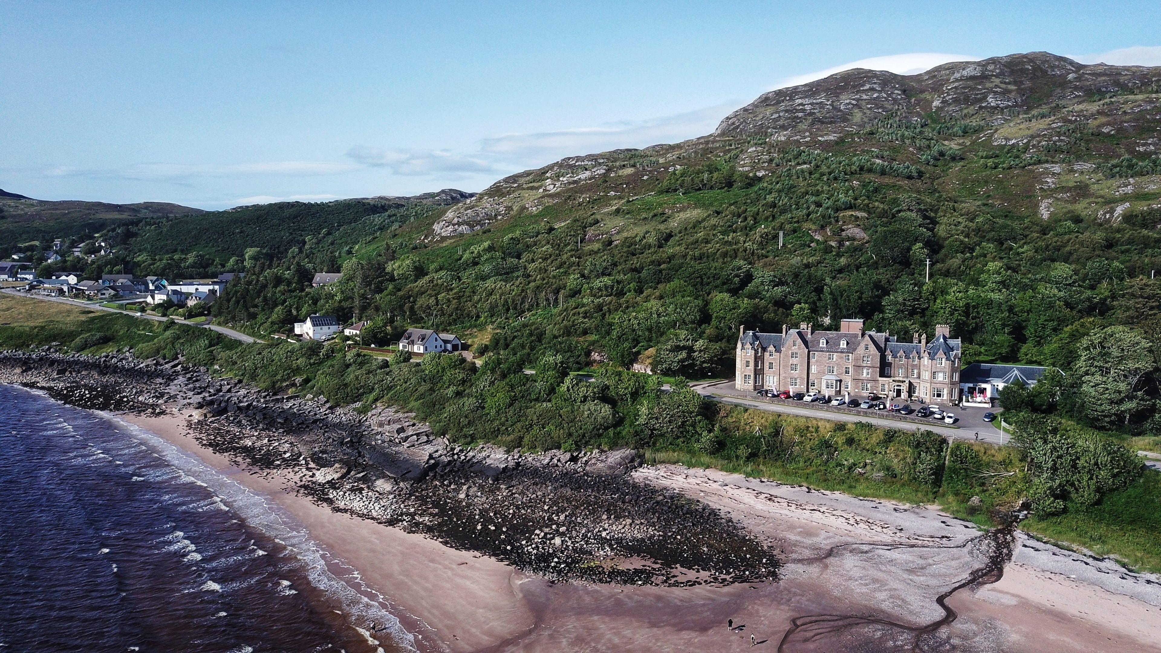A coastal hotel with a large building and smaller houses on a hillside.