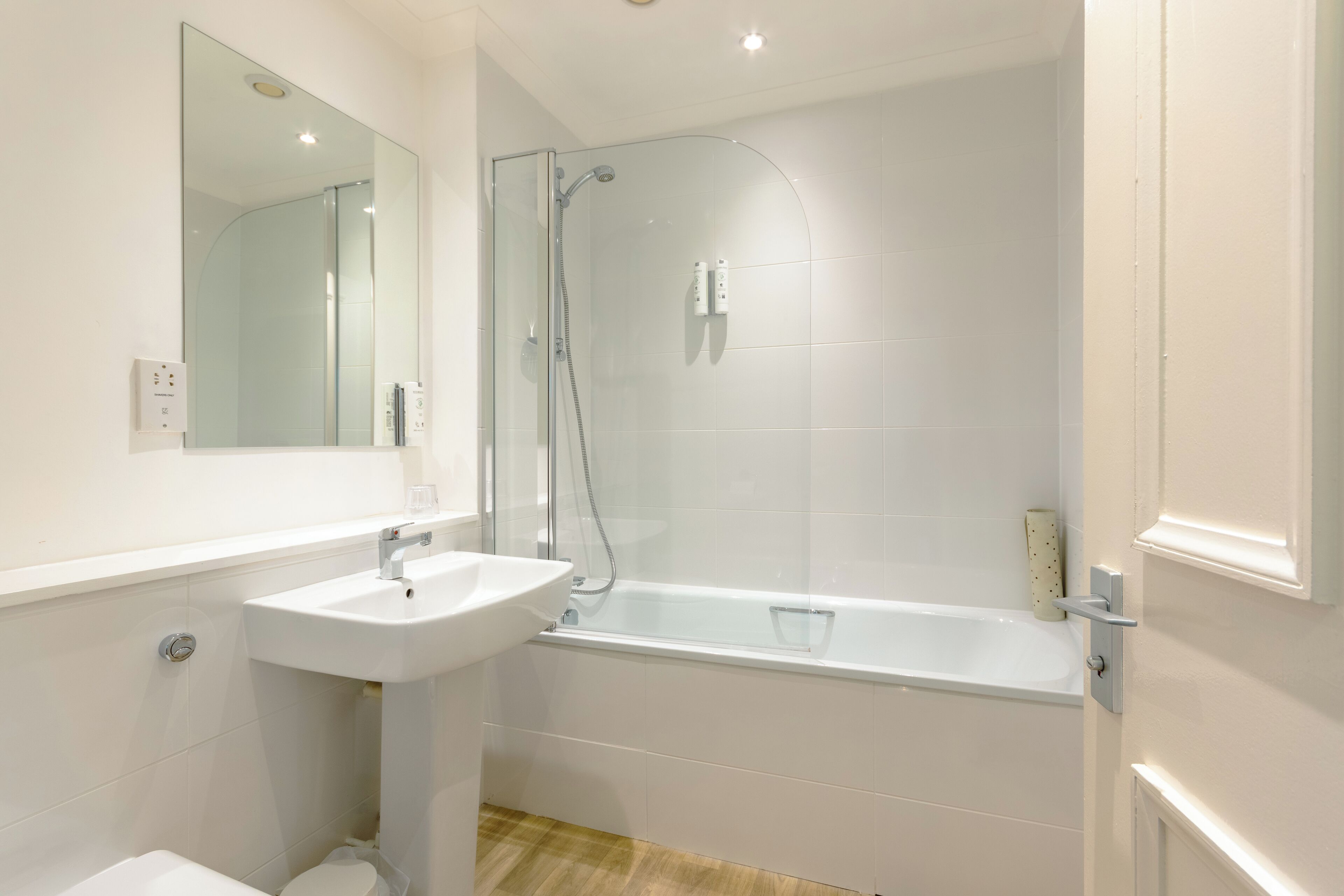 A modern bathroom with a glass-enclosed shower, a white sink, and a bathtub.
