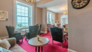 Una habitación amplia con ventanas grandes, varias zonas de estar y un candelabro.