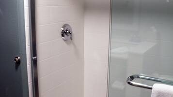 A glass-enclosed shower with a chrome showerhead and a towel rack.