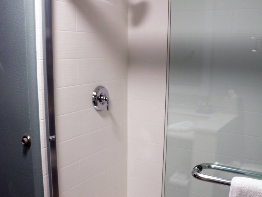 A glass-enclosed shower with a chrome showerhead and a towel rack.