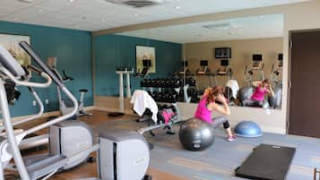 A gym with exercise equipment, a mirror, and a television.