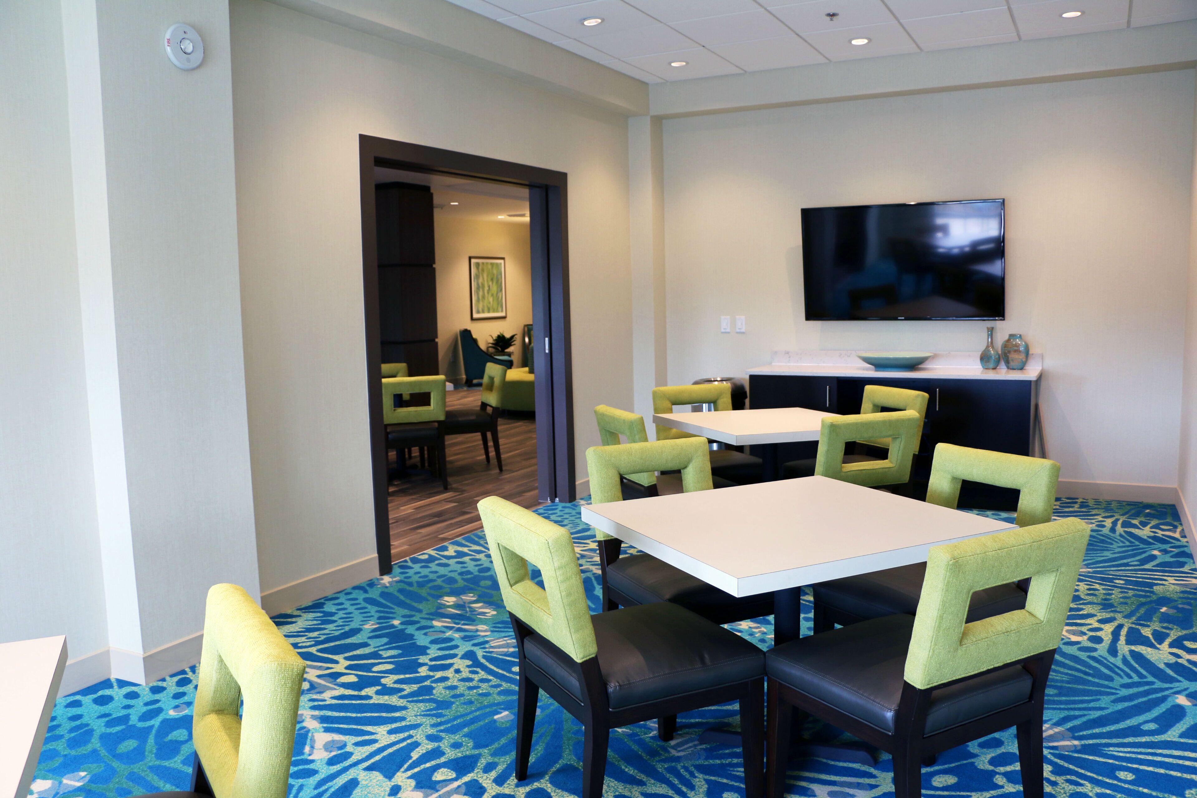 A conference room with a flat-screen TV, a table, and chairs.