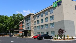 A Holiday Inn Express & Suites building with a stone facade, multiple windows, and a parking lot with cars. - Holiday Inn Express & Suites Hendersonville SE - Flat Rock by IHG (Flat Rock)