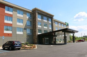 A multi-story hotel with a stone facade, a covered entrance, and a parking lot with cars.
