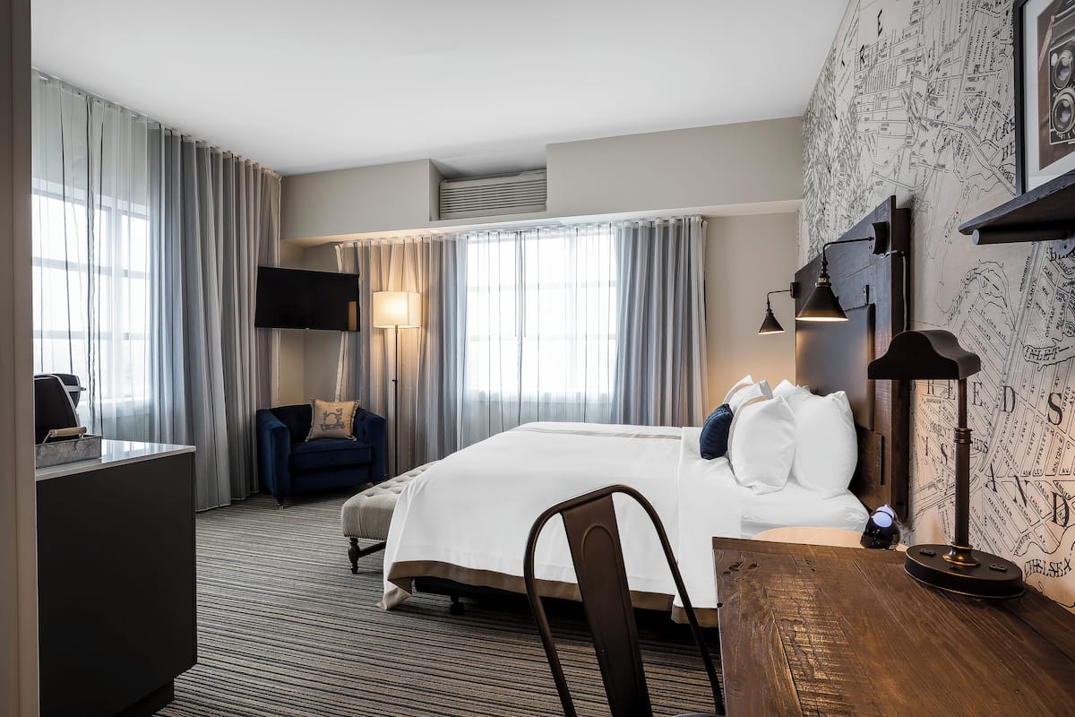 Une chambre d’hôtel avec un lit, un bureau, une chaise, une télévision et une carte accrochée au mur.
