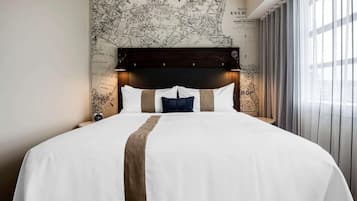 Una habitación de hotel con una cama grande, un cabecero oscuro y un mapa en la pared.