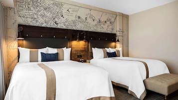 Habitación de hotel con dos camas, un mapa grande en la pared y un banco.
